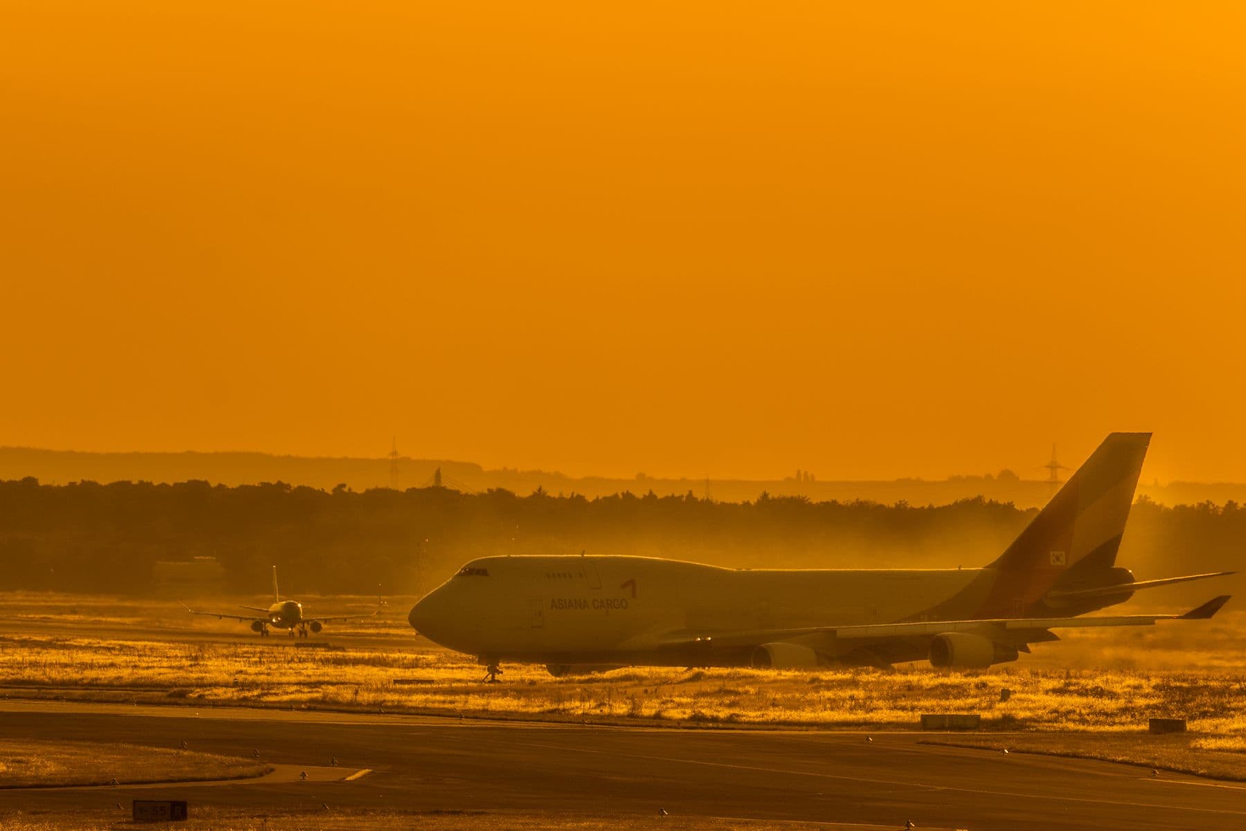 Wide-body freighter aircraft taxiing along the runway in golden evening light.