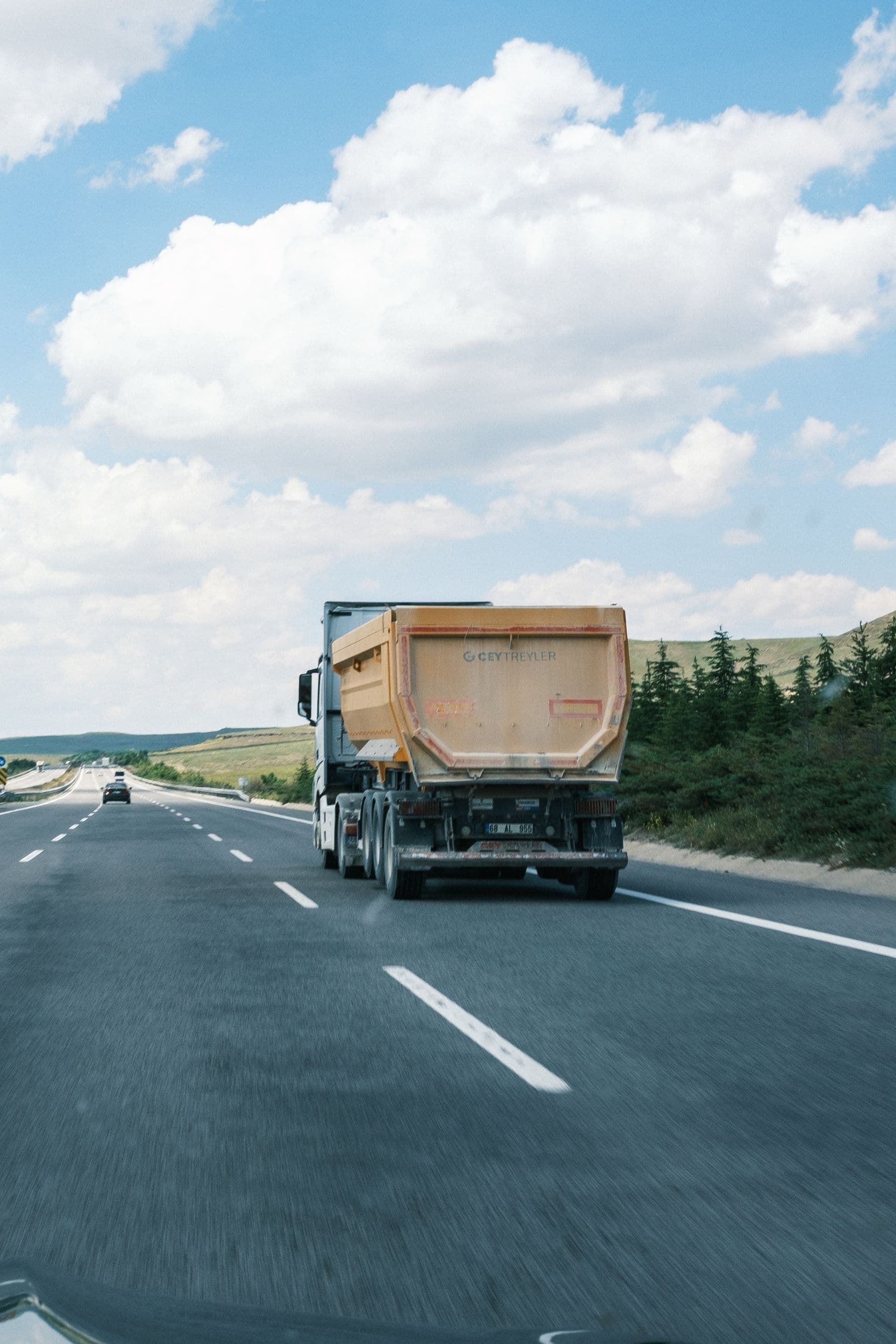 Freight lorry travelling along a highway beneath a bright blue sky.