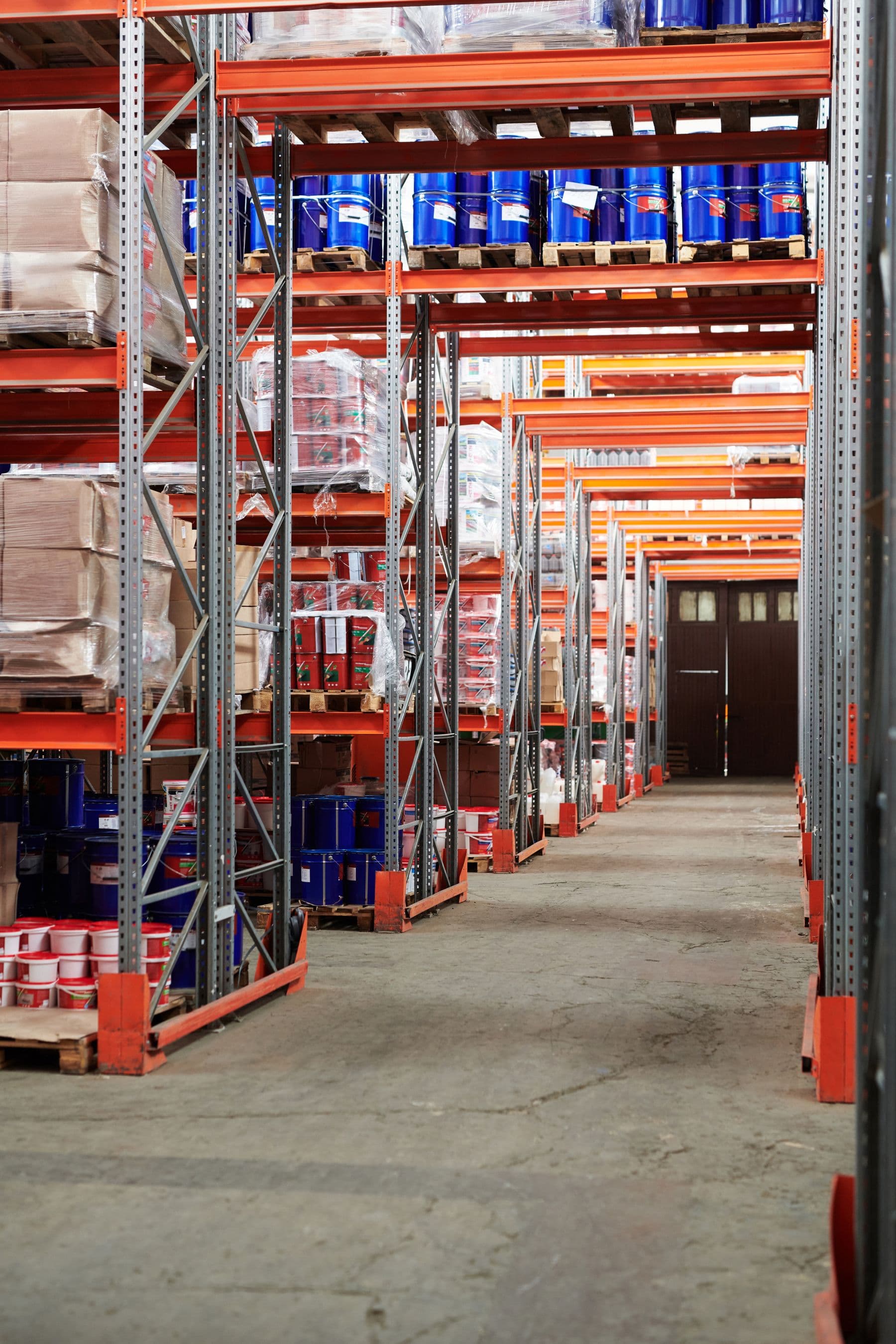 Interior of a distribution warehouse, with goods stacked on racking either side of a wide concrete aisle.